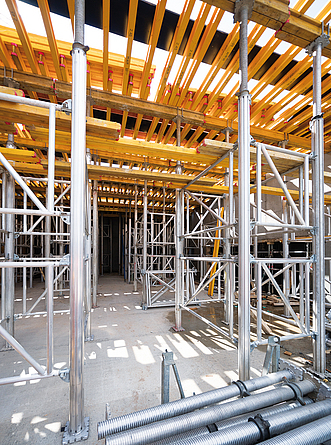 Blick durch einen Rohbau mit Holzträgerschalung auf Metallstützen