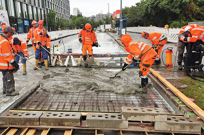 Straßenbauarbeiter beim Auftragen des Betons auf die Fahrbahn.