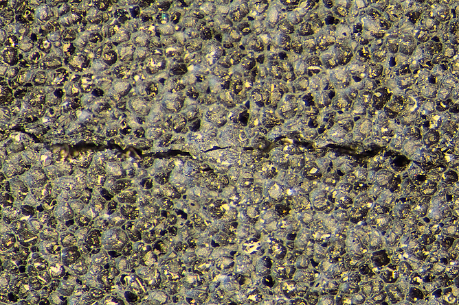 Die Mikroskop-Aufnahme mit zehnfacher Vergrößerung zeigt einen Riss in der obersten Schicht der Kleidung.