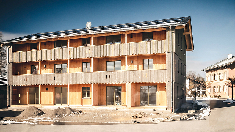Dreigeschossiges Mehrfamilienhaus mit Holzverkleidung im alpenländischen Stil