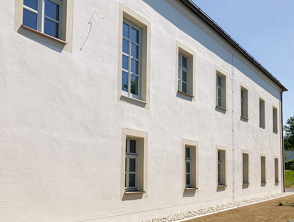 Blick auf die neu verputzte Fassade und die neu gestalteten Fensterumrahmungen.