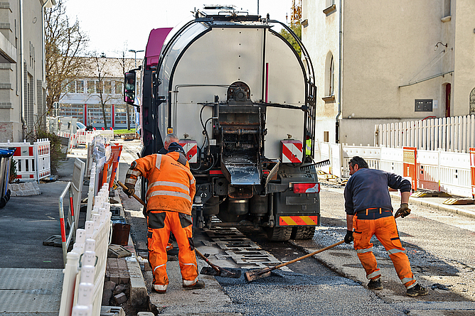 Straßenbauarbeiten zur Sicherstellung des Schichtenverbundes Zwei Straßenbauarbeiter stellen den Schichtenverbund sicher.