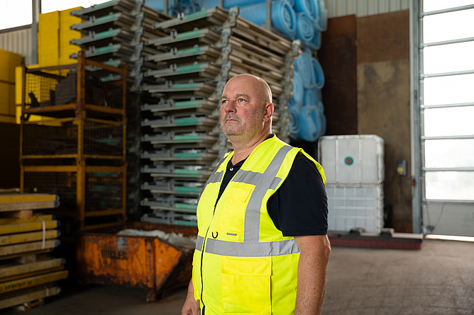 Lothar Hubert steht mit einer gelben Warnweste in einer Lagerhalle.