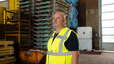 Lothar Hubert steht mit einer gelben Warnweste in einer Lagerhalle.