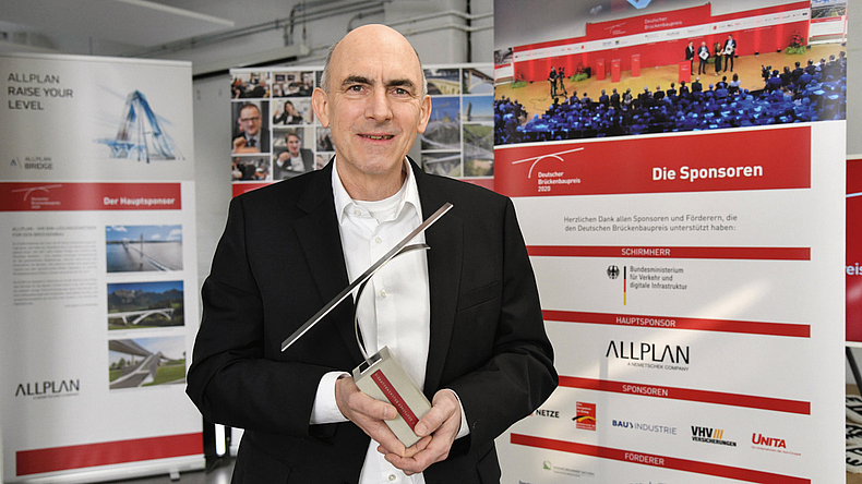 Eine Mann hält eine Auszeichnung in seinen Händen.