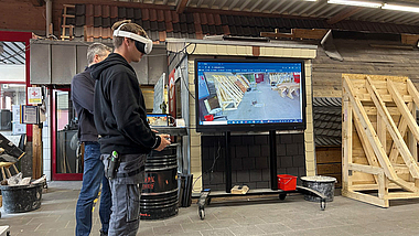 Flug-Simulator - EU-Projekt „Drones4VET“ Ein junger Mann mit VR-Brille testet den Drohnen-Flugsimulator en einem Bildschirm im Bildungszentrum der Baugewerbe.